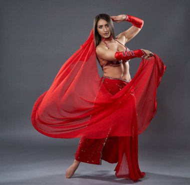 Arap kadın dansçı, gri arka planda kırmızı, ışıltılı kostümlü.