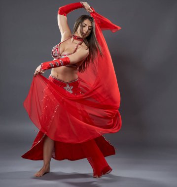 Arap kadın dansçı, gri arka planda kırmızı, ışıltılı kostümlü.