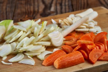 Tahtada doğranmış pırasa, havuç ve havuç.