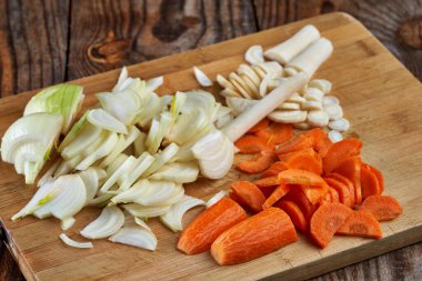 Tahtada doğranmış pırasa, havuç ve havuç.