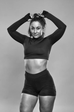 Ayrıca kendine güvenen genç bir kadın gri arka plan üzerinde spor yapıyor.