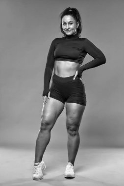 Ayrıca kendine güvenen genç bir kadın gri arka plan üzerinde spor yapıyor.