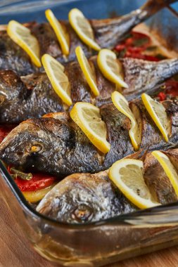Oven baked broiled bream with vegetables and lemon