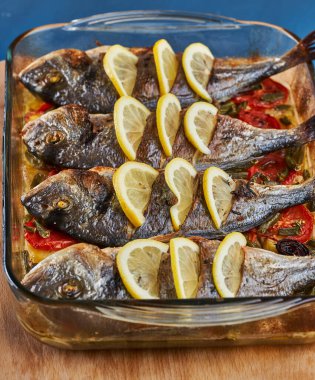Oven baked broiled bream with vegetables and lemon