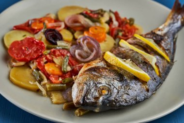 Oven baked broiled bream with vegetables and lemon