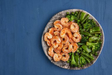 Lezzetli kırmızı kral karidesleri wok 'ta mavi arka planda hazırlandı.