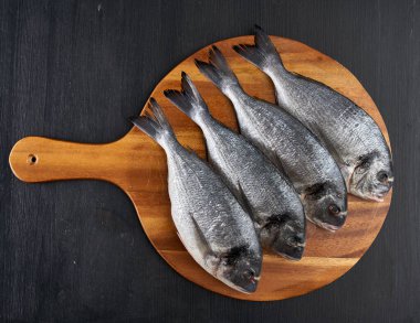 Raw breams on a black wooden board flat lay shot