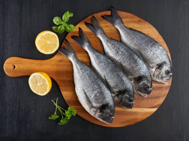 Raw breams on a black wooden board flat lay shot