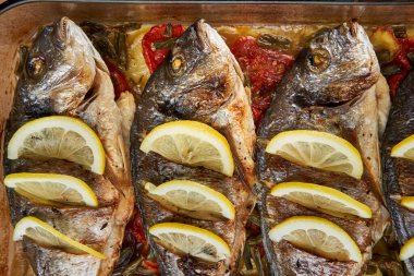 Oven baked broiled bream with vegetables and lemon