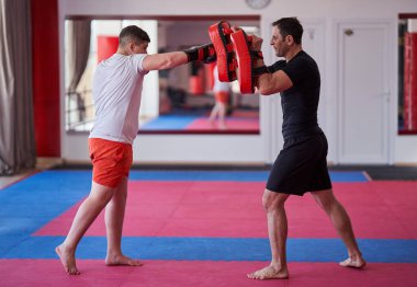 Kilolu kickbox dövüşçüsü koçuyla yumruk tokuşturuyor.