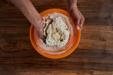 Bir kadının elleri tahtadan hamur işi yoğuruyor.