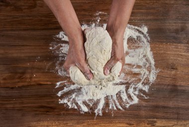 Bir kadının elleri tahtadan hamur işi yoğuruyor.