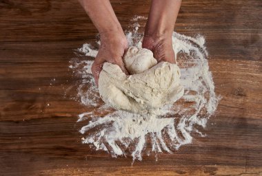 Bir kadının elleri tahtadan hamur işi yoğuruyor.