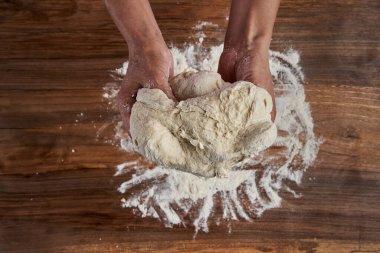 Bir kadının elleri tahtadan hamur işi yoğuruyor.