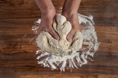 Bir kadının elleri tahtadan hamur işi yoğuruyor.