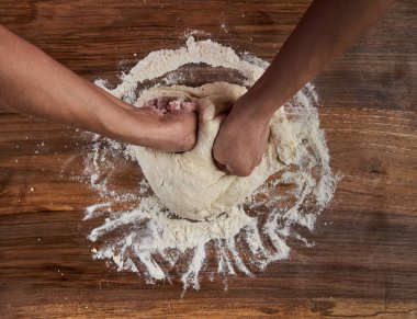 Bir kadının elleri tahtadan hamur işi yoğuruyor.