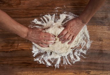 Bir kadının elleri tahtadan hamur işi yoğuruyor.