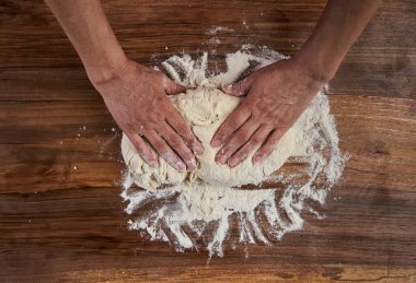 Bir kadının elleri tahtadan hamur işi yoğuruyor.