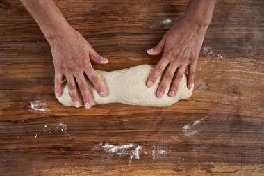 Bir kadının elleri tahtadan hamur işi yoğuruyor.