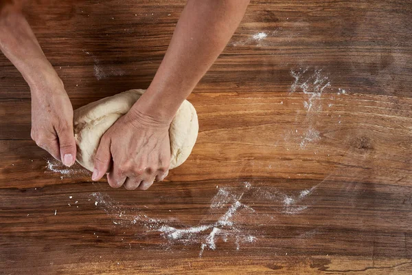 Bir kadının elleri tahtadan hamur işi yoğuruyor.