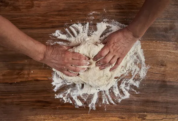 Bir kadının elleri tahtadan hamur işi yoğuruyor.