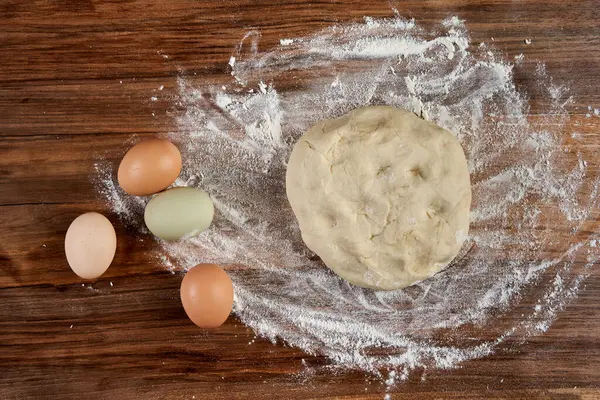 Hamur hamuru, yumurta ve un yoğurma tahtasında.