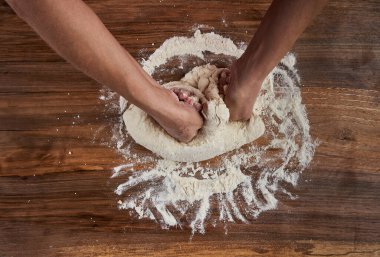 Bir kadının elleri tahtadan hamur işi yoğuruyor.