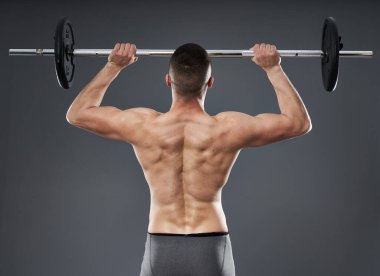 Gri arka planda izole edilmiş halterli genç sporcu eğitimi.