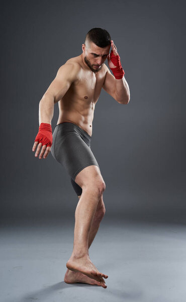 MMA fighter throwing a leg kick, studio shot isolated on gray background