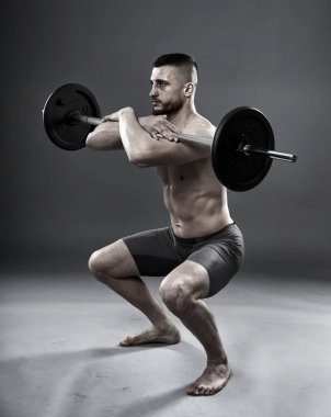 Gri arka planda izole edilmiş halterli genç sporcu eğitimi.