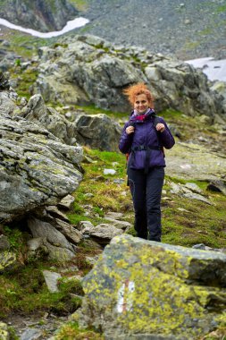 Yağmurlu bir günde dağlarda yürüyüş yapan bir kadın yürüyüşçü.