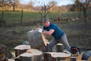 Koca kayın kütüklerini ağır baltasıyla parçalayan güçlü bir oduncu.