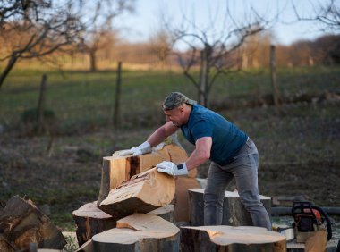 Koca kayın kütüklerini ağır baltasıyla parçalayan güçlü bir oduncu.