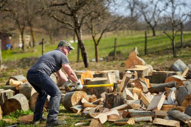 Koca kayın kütüklerini ağır baltasıyla parçalayan güçlü bir oduncu.