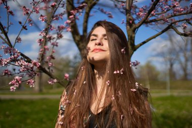 Parkta çiçek açmış kiraz ağaçları olan genç İspanyol kadın.