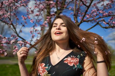 Parkta çiçek açmış kiraz ağaçları olan genç İspanyol kadın.