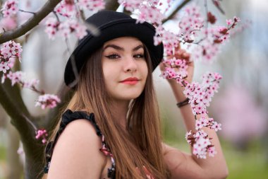 Parkta çiçek açmış kiraz ağaçları olan genç İspanyol kadın.