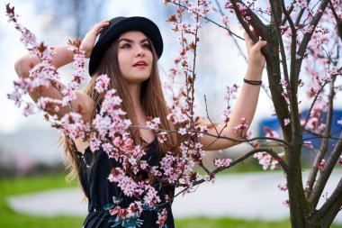Parkta çiçek açmış kiraz ağaçları olan genç İspanyol kadın.