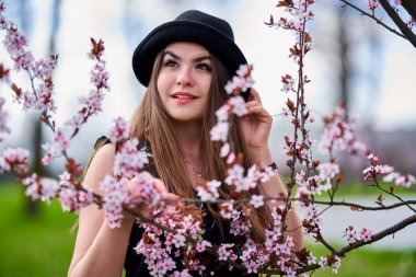 Parkta çiçek açmış kiraz ağaçları olan genç İspanyol kadın.