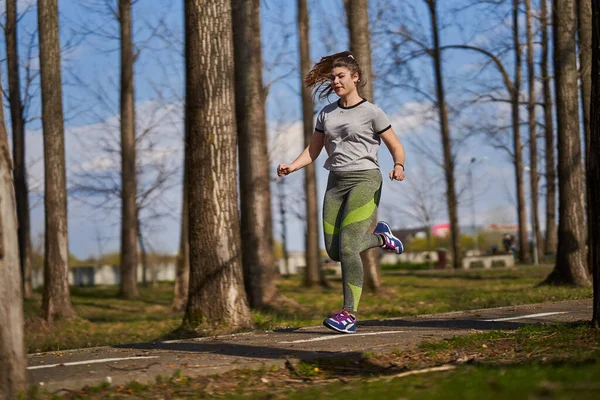 春の公園を走るサイズプラス女性 — ストック写真