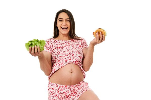怀孕妇女在生菜和汉堡包之间做出选择 被白色背景隔离 — 图库照片