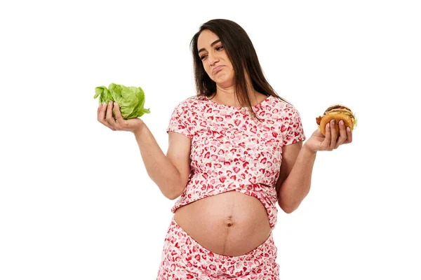 怀孕妇女在生菜和汉堡包之间做出选择 被白色背景隔离 — 图库照片