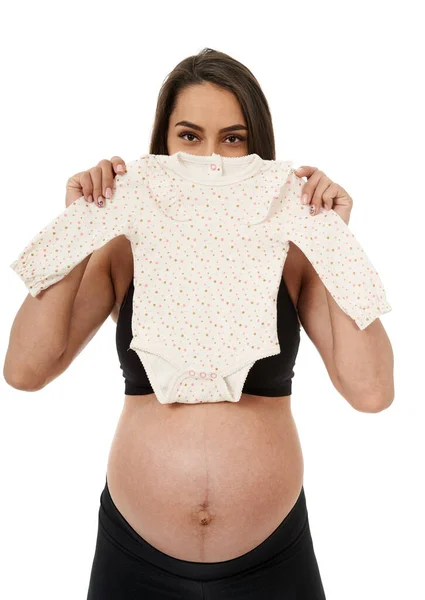 怀孕的准妈妈抱着她未来女儿的婴儿衣服 被白色背景隔离 — 图库照片