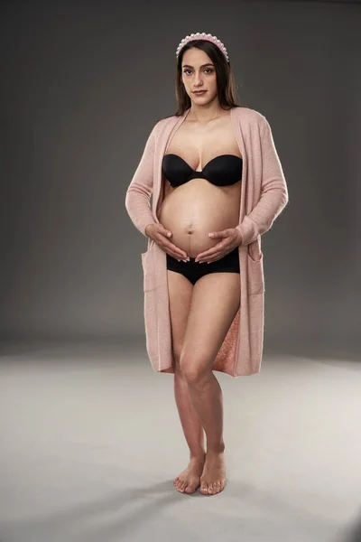 Gravid Kvinna Svart Underkläder Och Beige Mantel Poserar Grå Bakgrund — Stockfoto