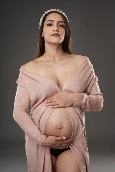 妊娠中の女性で黒ランジェリーとベージュローブポーズ上の灰色の背景 — ストック写真