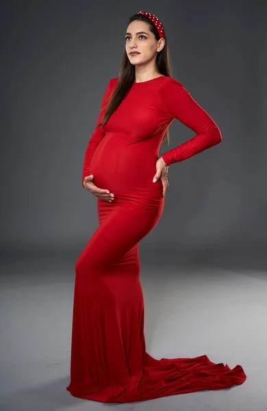 Красивая Беременная Женщина Красном Платье Шарф Голове Позирует Изолированно Сером — стоковое фото