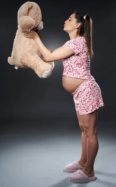 Zwangere Vrouw Pyjama Met Een Grote Pluizige Beer Speelgoed Poseren — Stockfoto