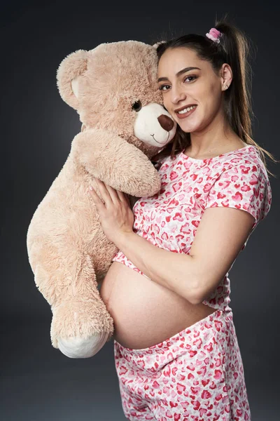 Femeie Gravidă Pijama Jucărie Mare Urs Pufos Pozând Fundal Gri — Fotografie, imagine de stoc