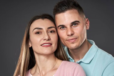 Gri arka plana karşı poz veren beyaz bir çift.