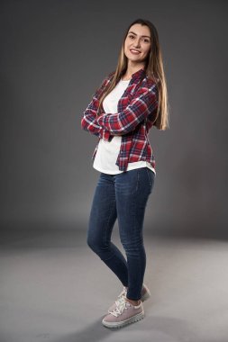 Gri arka planda, ekose gömlekli genç bir kadının boyu.